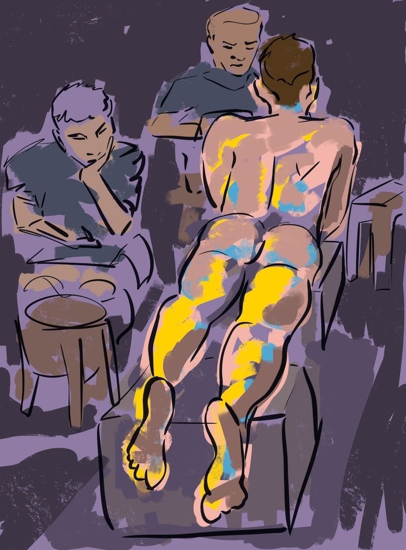 Jake lying prone on boxes while artists draw his butt.